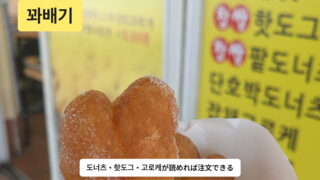 屋台で買ったクァベギと、도너츠・핫도그・고로케が並ぶ韓国語の看板